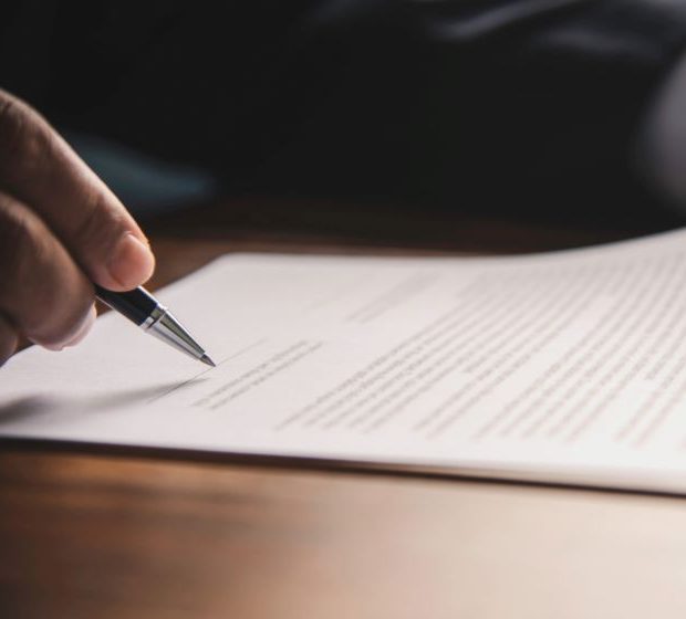A pen held over a printed document on a desk